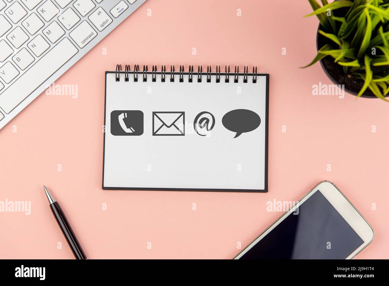 Contact us symbol on note pad on office desk Stock Photo