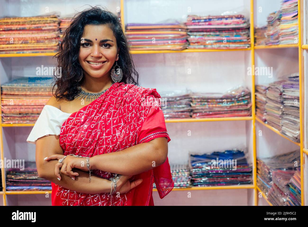 business lady in red traditional sari and jewelery clothes shop owner cashmere yak wool shawls.female seller in goa india arambol sale shop.designer Stock Photo