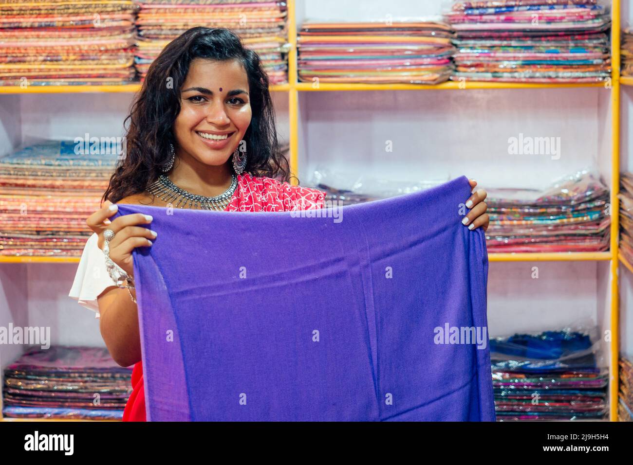 business lady in red traditional sari and jewelery clothes shop owner cashmere yak wool shawls.female seller in goa india arambol sale shop.designer Stock Photo