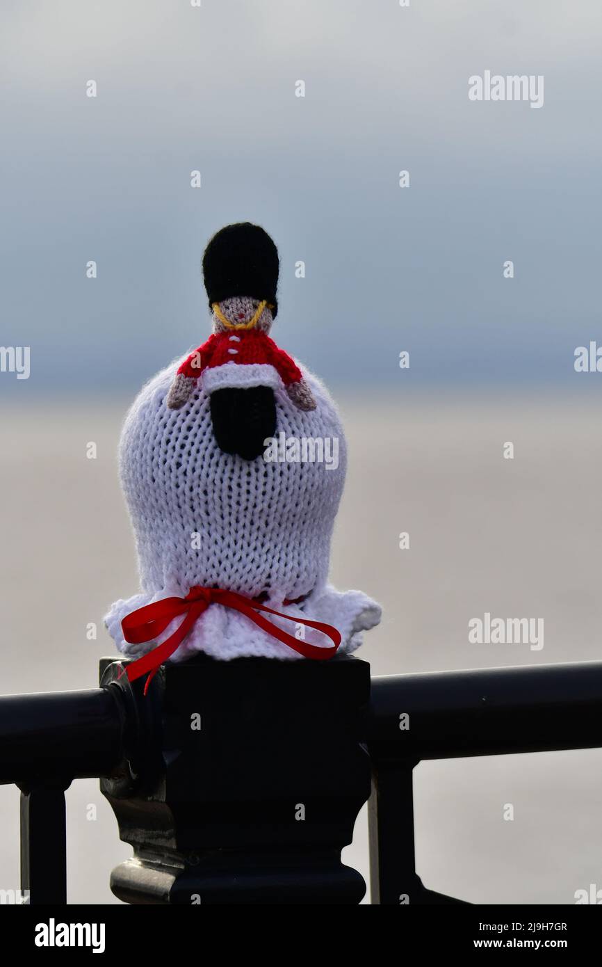Clevedon, UK. 23rd May, 2022. On a mild Monday evening at Clevedon Seafront, knitted hats of all colors are seen sitting on top of the safety railing which run the entire length of the promenade getting ready for the Queen's Platinum Jubilee. Picture Credit: Robert Timoney/Alamy Live News Stock Photo