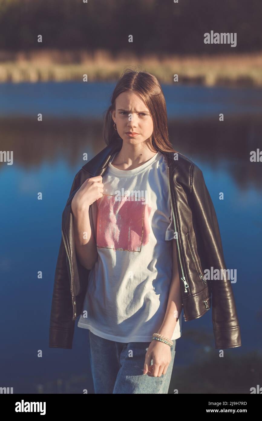 Portrait of a beautiful happy teenage girl in leather jacket outdoors ...