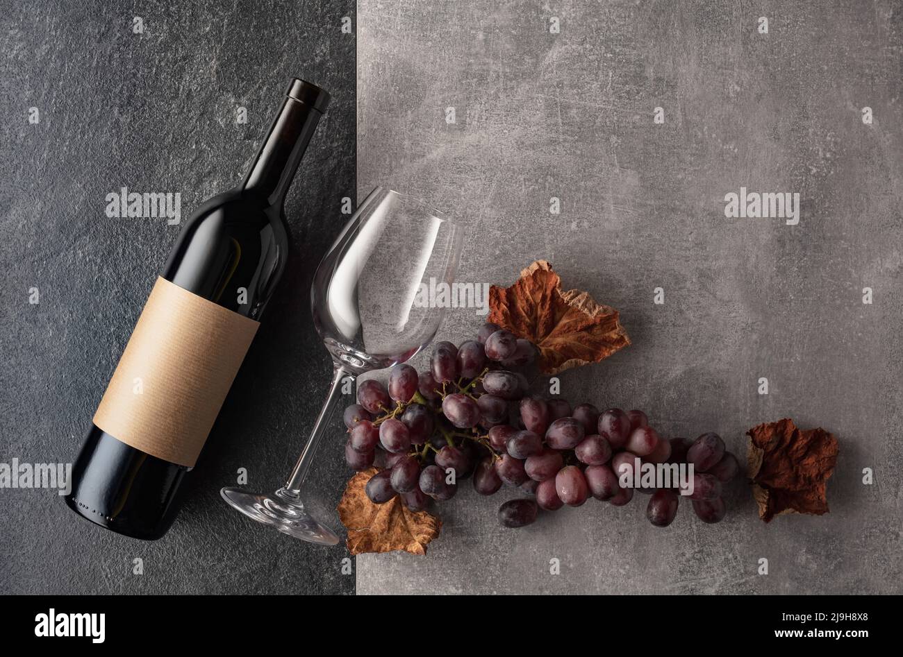 Red wine with grapes on a stone background. On a bottle empty label