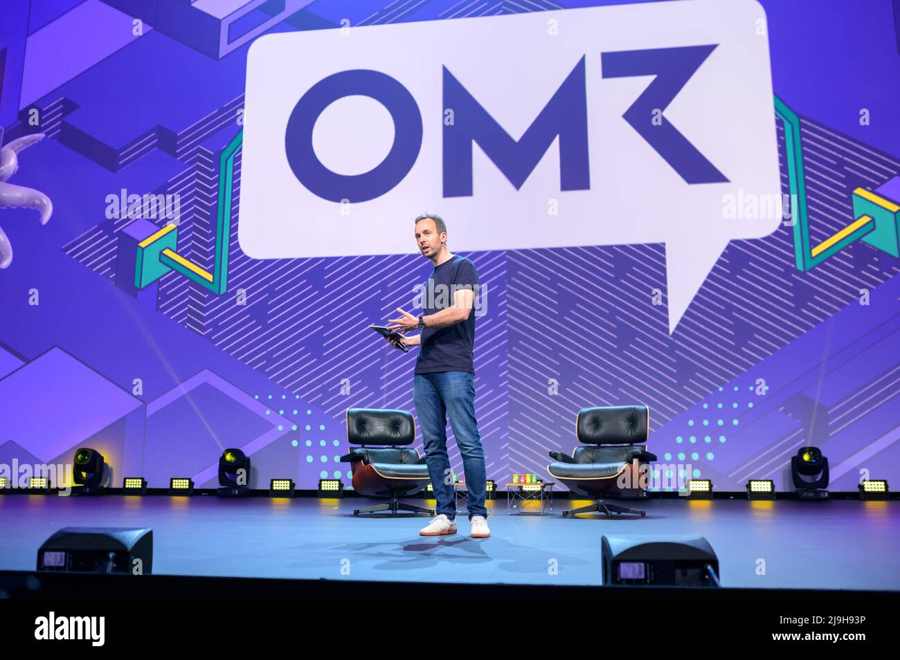 Hamburg, Germany. 18th May, 2022. OMR CEO Philipp Westermeyer moderates on a stage in front of the OMR logo. The OMR digital festival in Hamburg focuses on a combination of trade fair, workshops and party. Credit: Jonas Walzberg/dpa/Alamy Live News Stock Photo