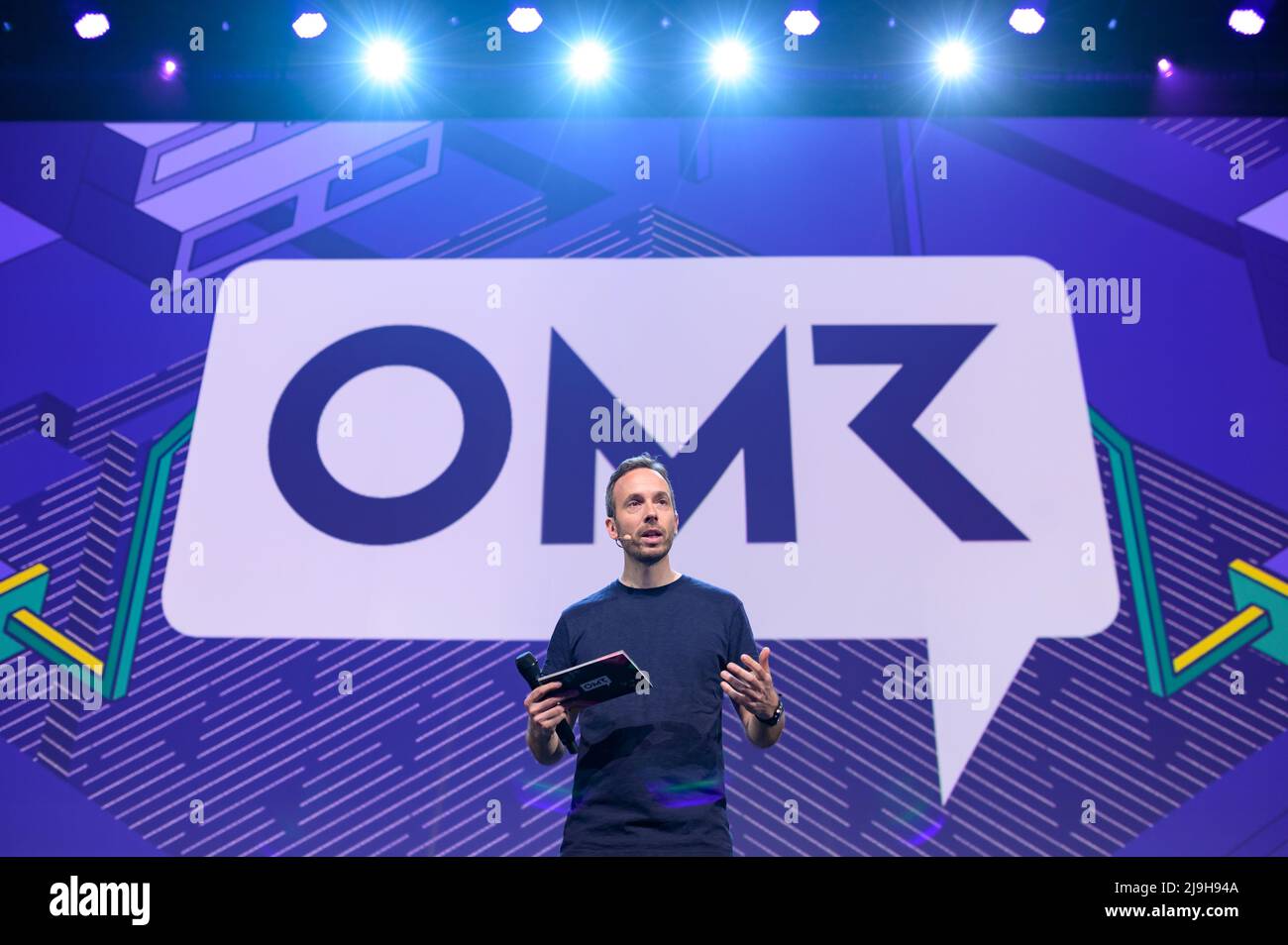 Hamburg, Germany. 18th May, 2022. OMR CEO Philipp Westermeyer moderates on a stage in front of the OMR logo. The OMR digital festival in Hamburg focuses on a combination of trade fair, workshops and party. Credit: Jonas Walzberg/dpa/Alamy Live News Stock Photo