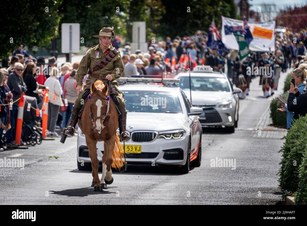 Rider in military uniform on horse back followed by police car carrying veterans during ANZAC march. Glen Innes, NSW Australia Stock Photo