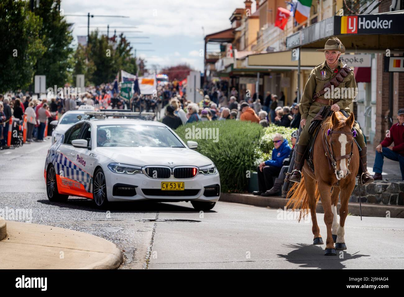 Rider in military uniform on horse back followed by police car carrying veterans during ANZAC march. Glen Innes, NSW Australia Stock Photo