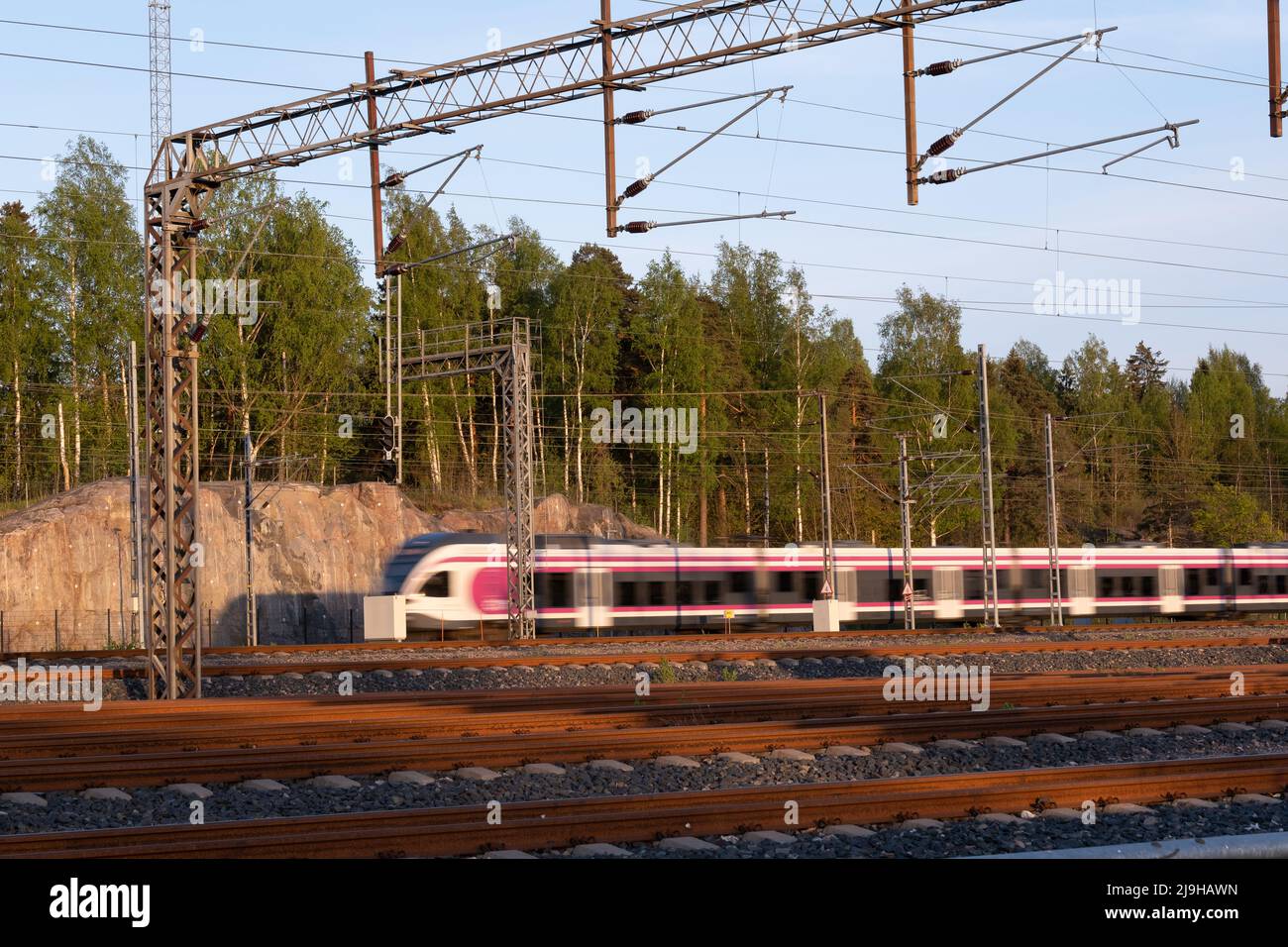 Helsinki / Finland - MAY 22, 2022: Unfocus train passing by a railway junction during the sunset Stock Photo