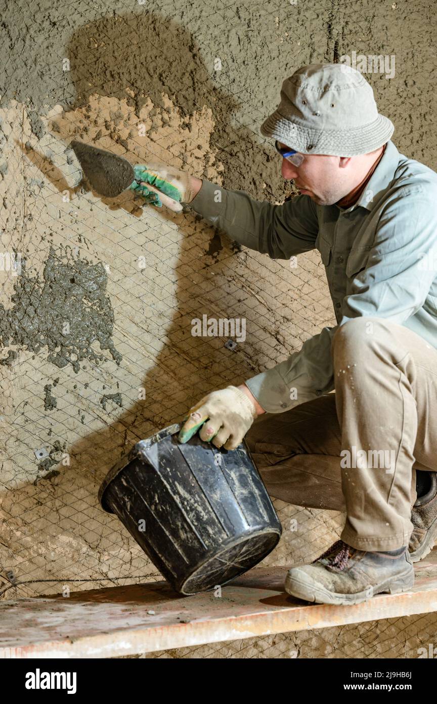A man throws concrete mortar on the wall, the first layer of plaster on