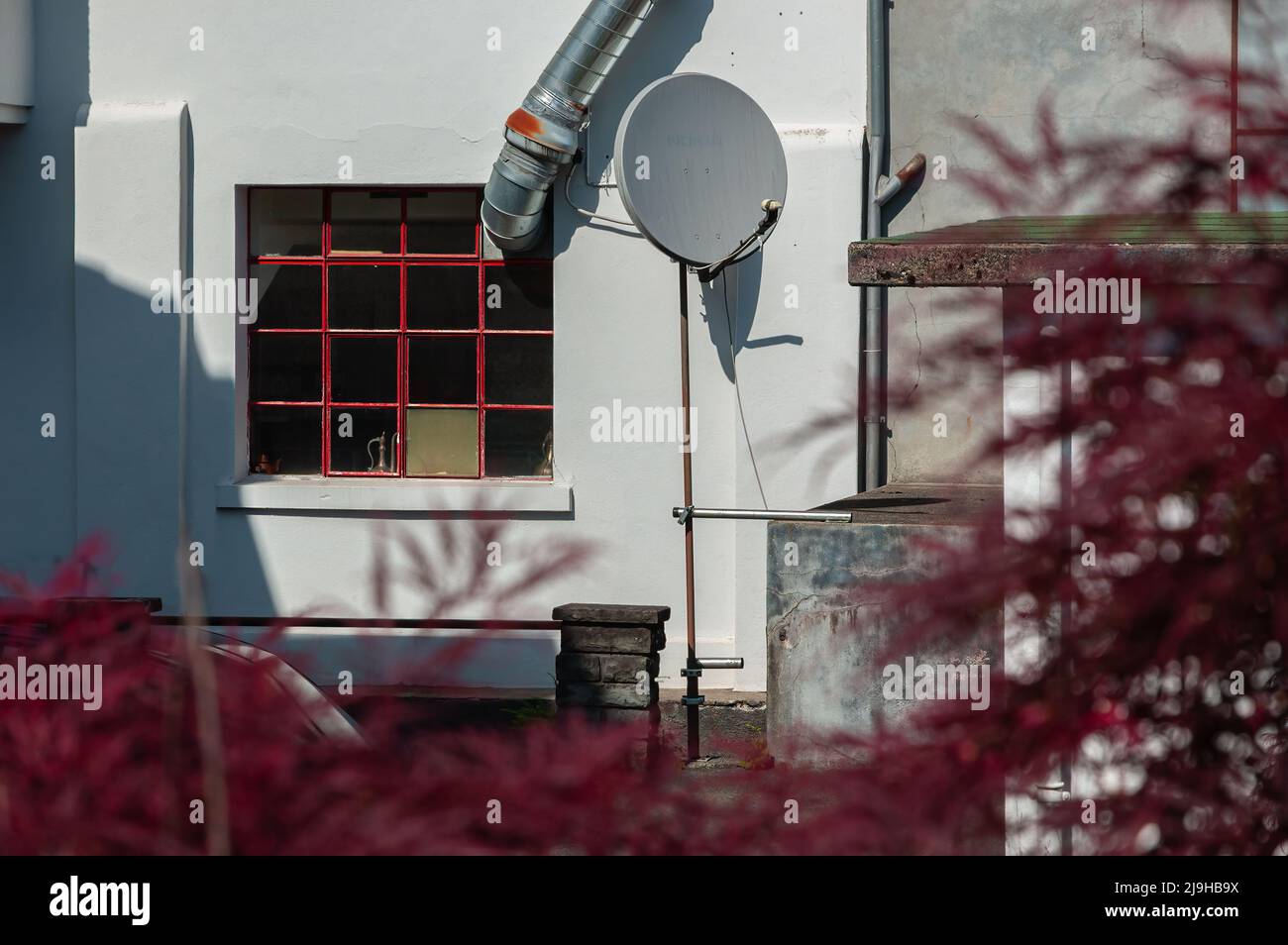 Satellite dish in the yard of a and ventilation pipe through