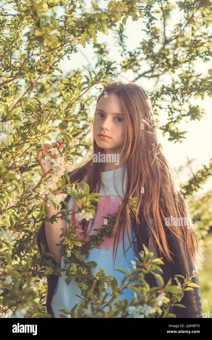 portrait of a beautiful happy teenage girl outdoors in spring a girl poses in a blooming spring garden 2J9HBTD