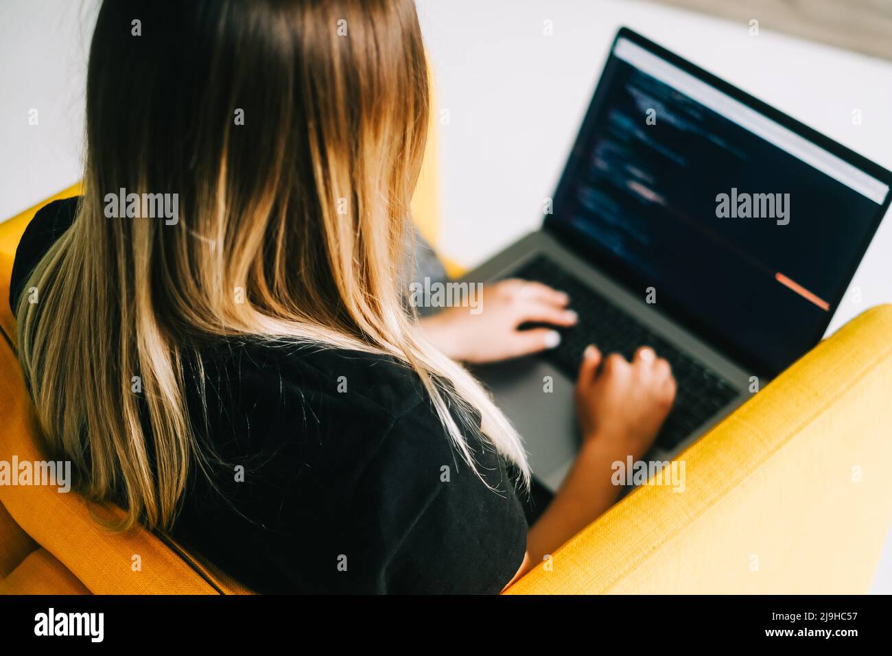 Young woman mobile developer writes program code on a computer, programmer work. Stock Photo
