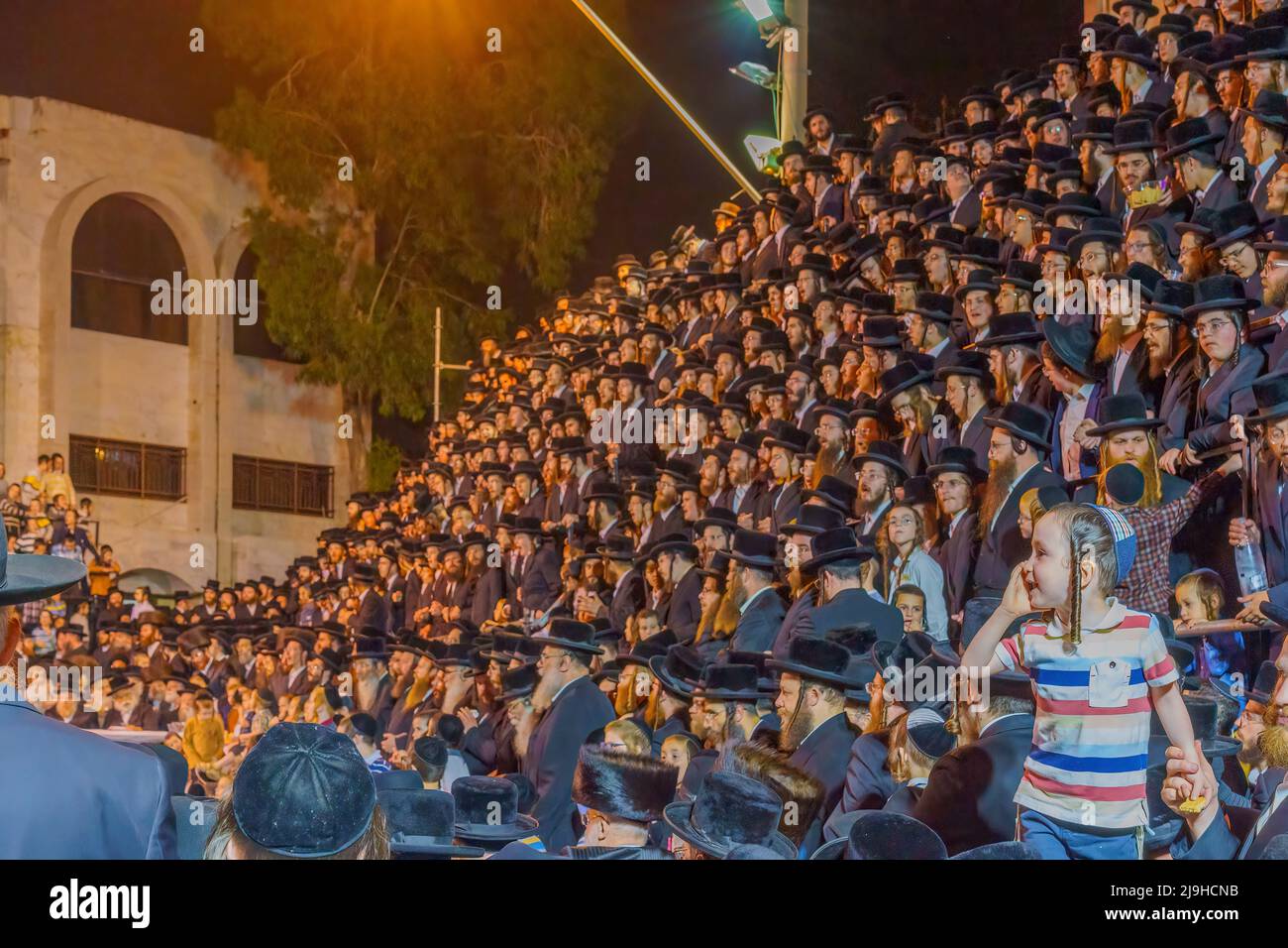Haifa, Israel - May 18, 2022: Lag BaOmer holyday celebration of the ultra-orthodox Jewish Vizhnitz community, with a kid watching the men crowd. Haifa Stock Photo