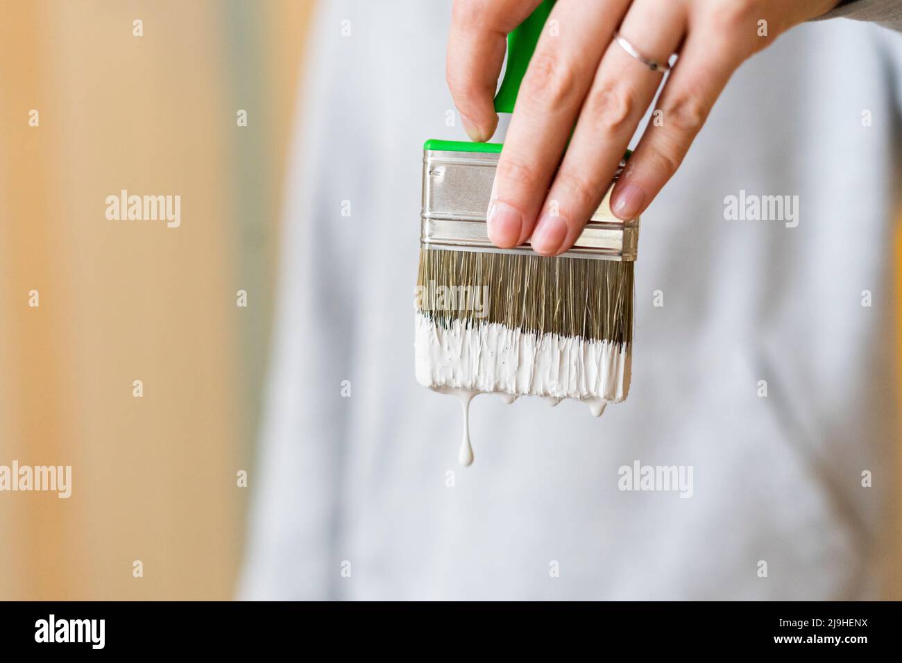 Woman holding paintbrush with dripping white paint Stock Photo - Alamy