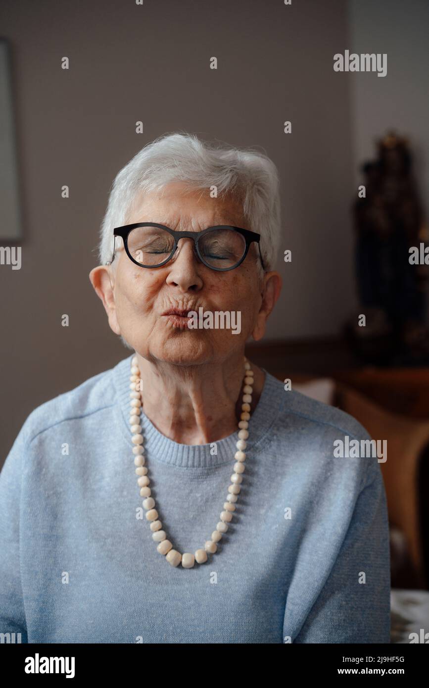 Senior woman with puckering face at home Stock Photo
