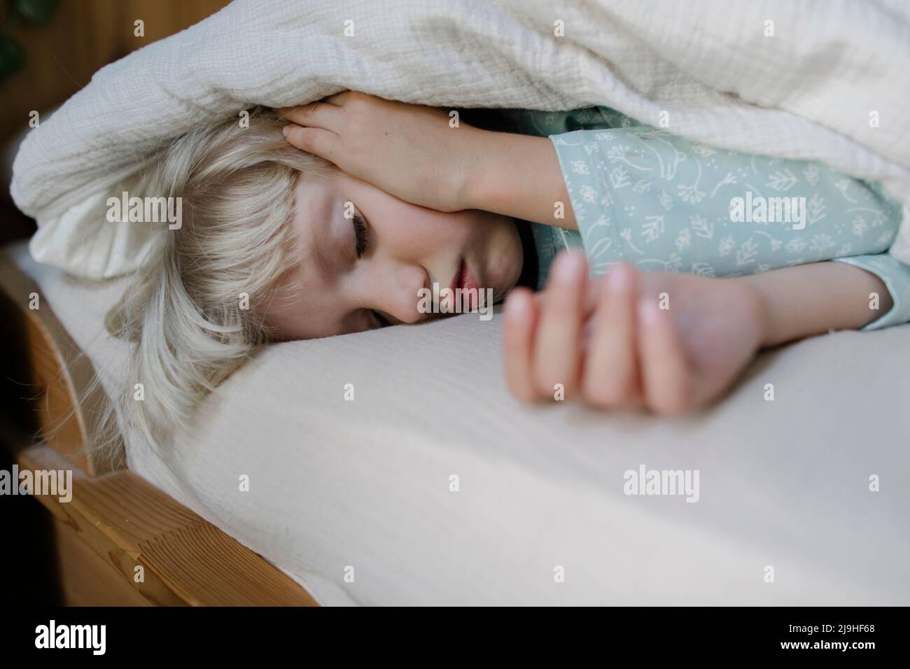 Girl sleeping under blanket on bed at home Stock Photo Alamy