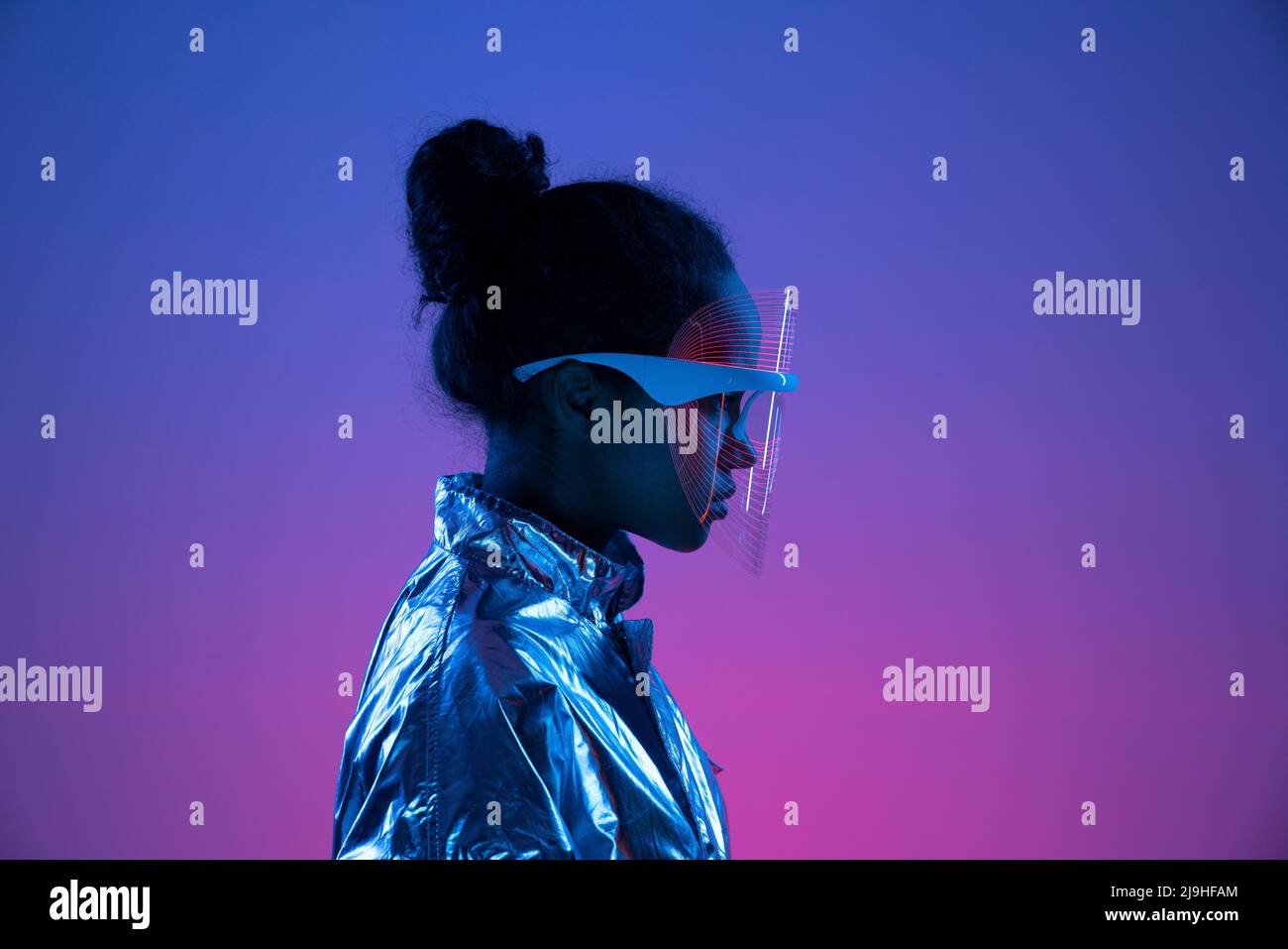 Young woman wearing futuristic smart glasses against multi-colored background Stock Photo