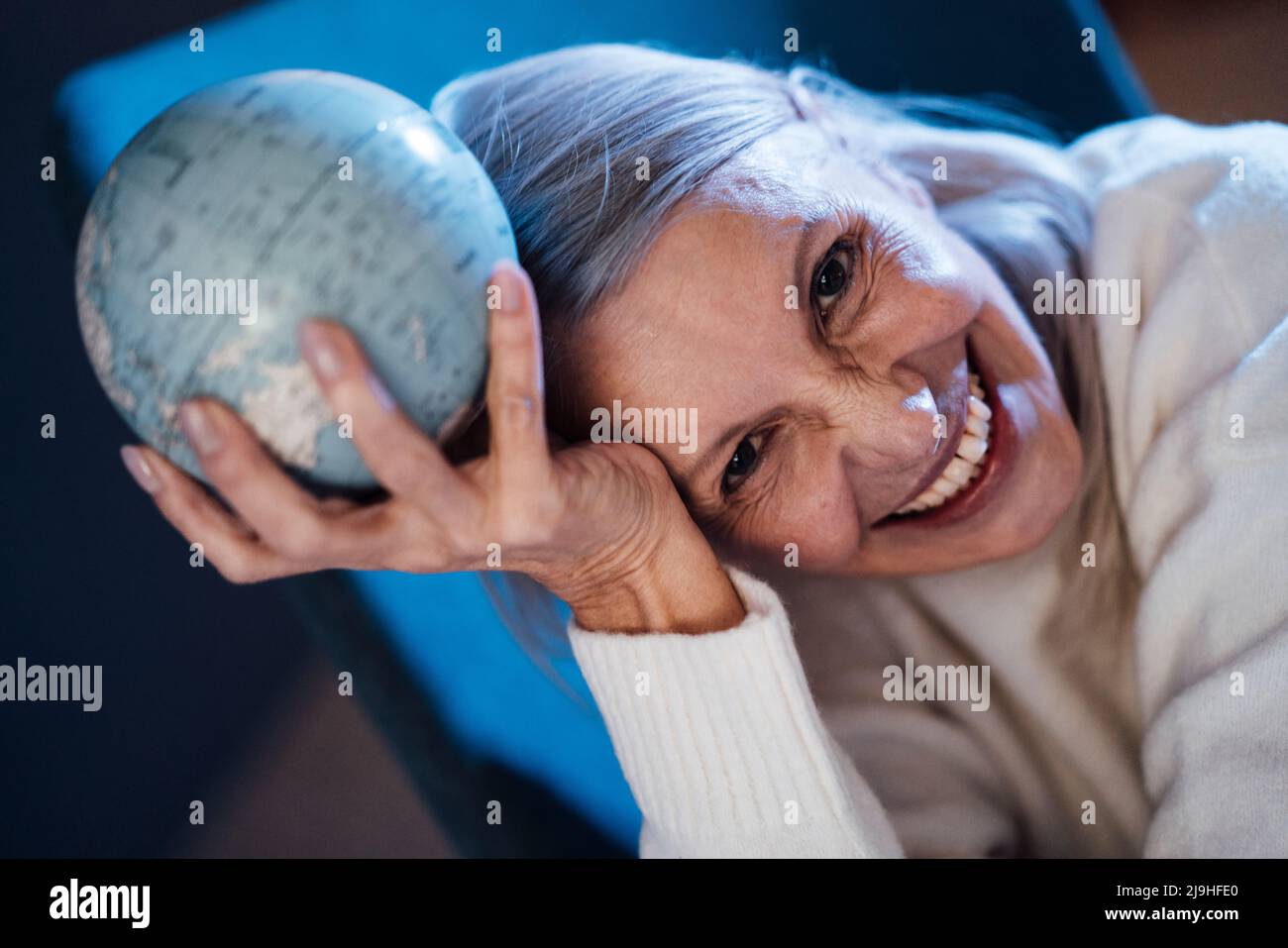 Happy senior woman holding globe in hand Stock Photo