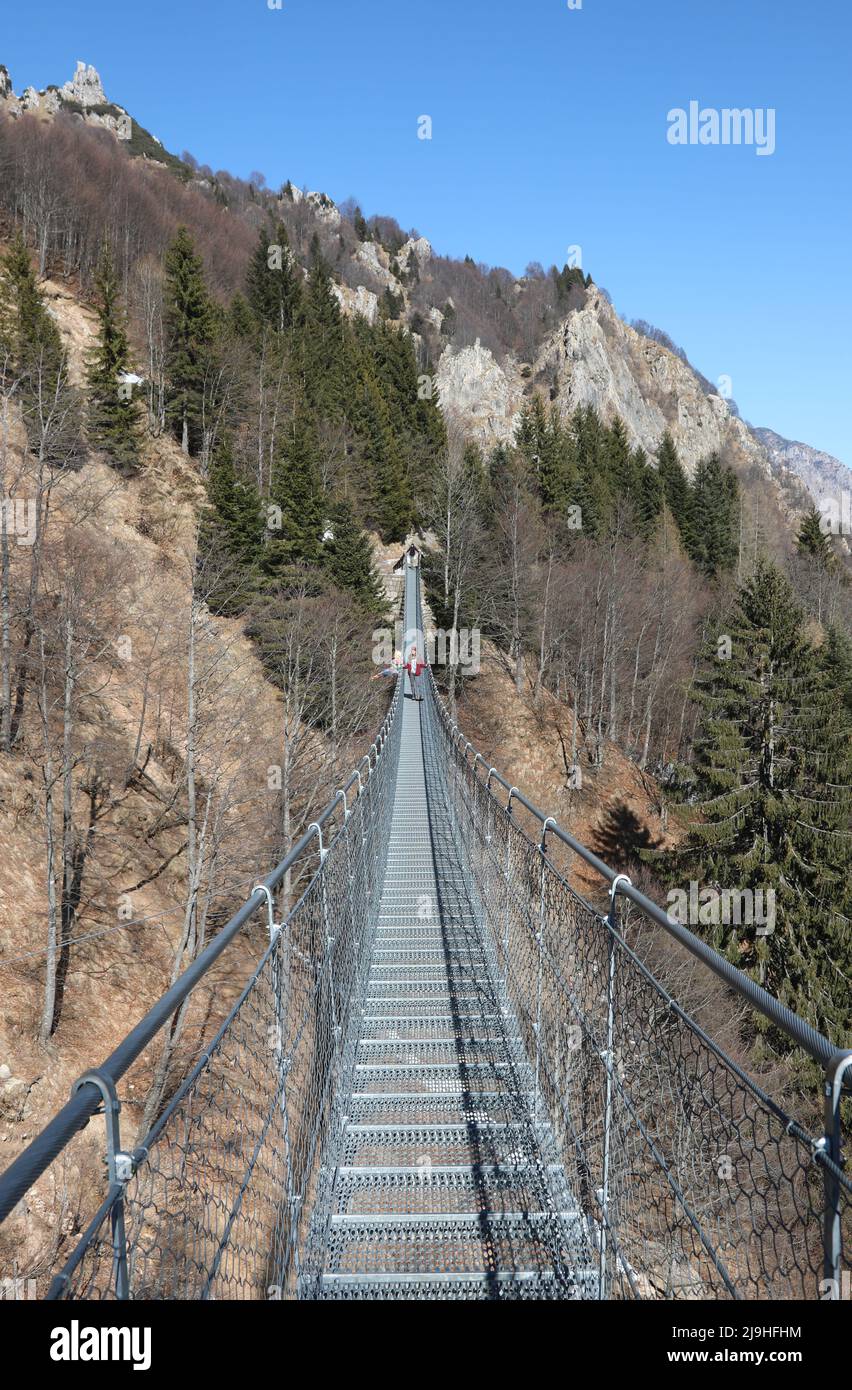 very long suspension bridge made of sturdy steel ropes connecting the two ends of a landslide in the mountains Stock Photo