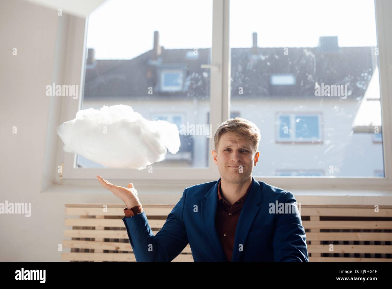 Smiling businessman with levitating cloud network in office Stock Photo