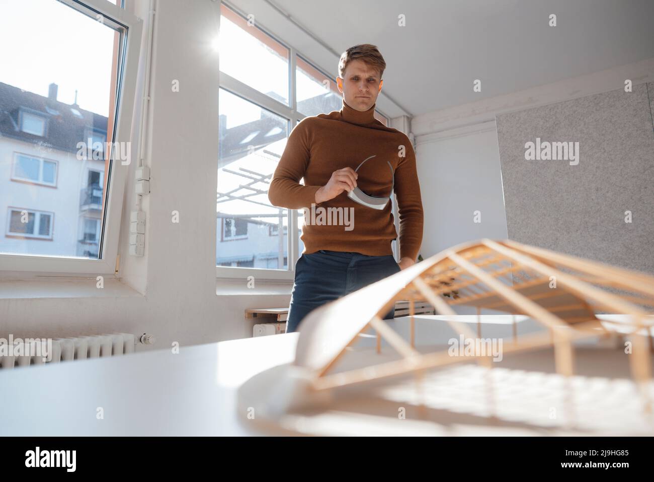 Architect holding virtual reality simulator looking at leaf shaped model in office Stock Photo