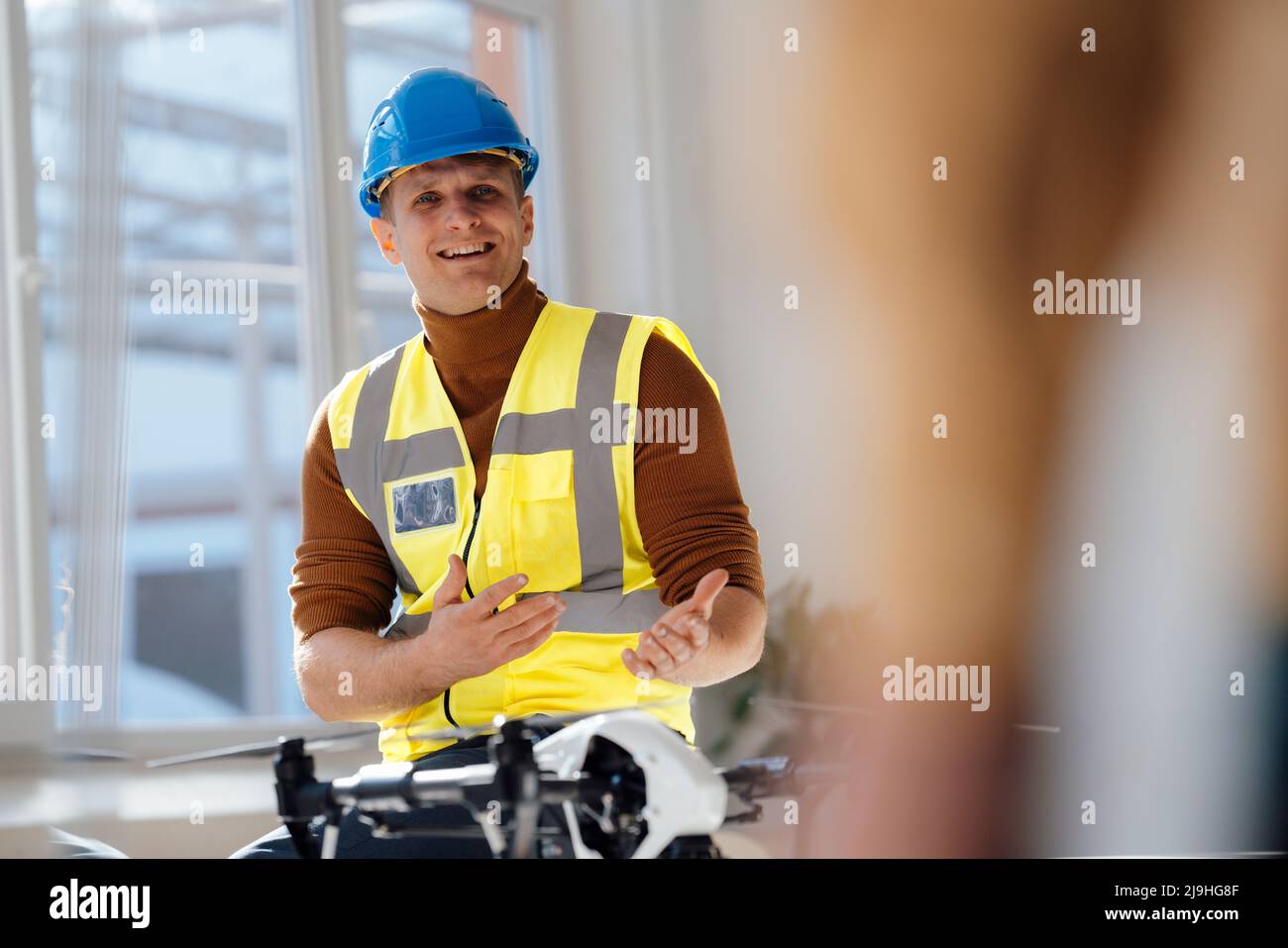 Smiling Engineer Smiling engineer wearing reflective clothing and hardhat sitting in ...