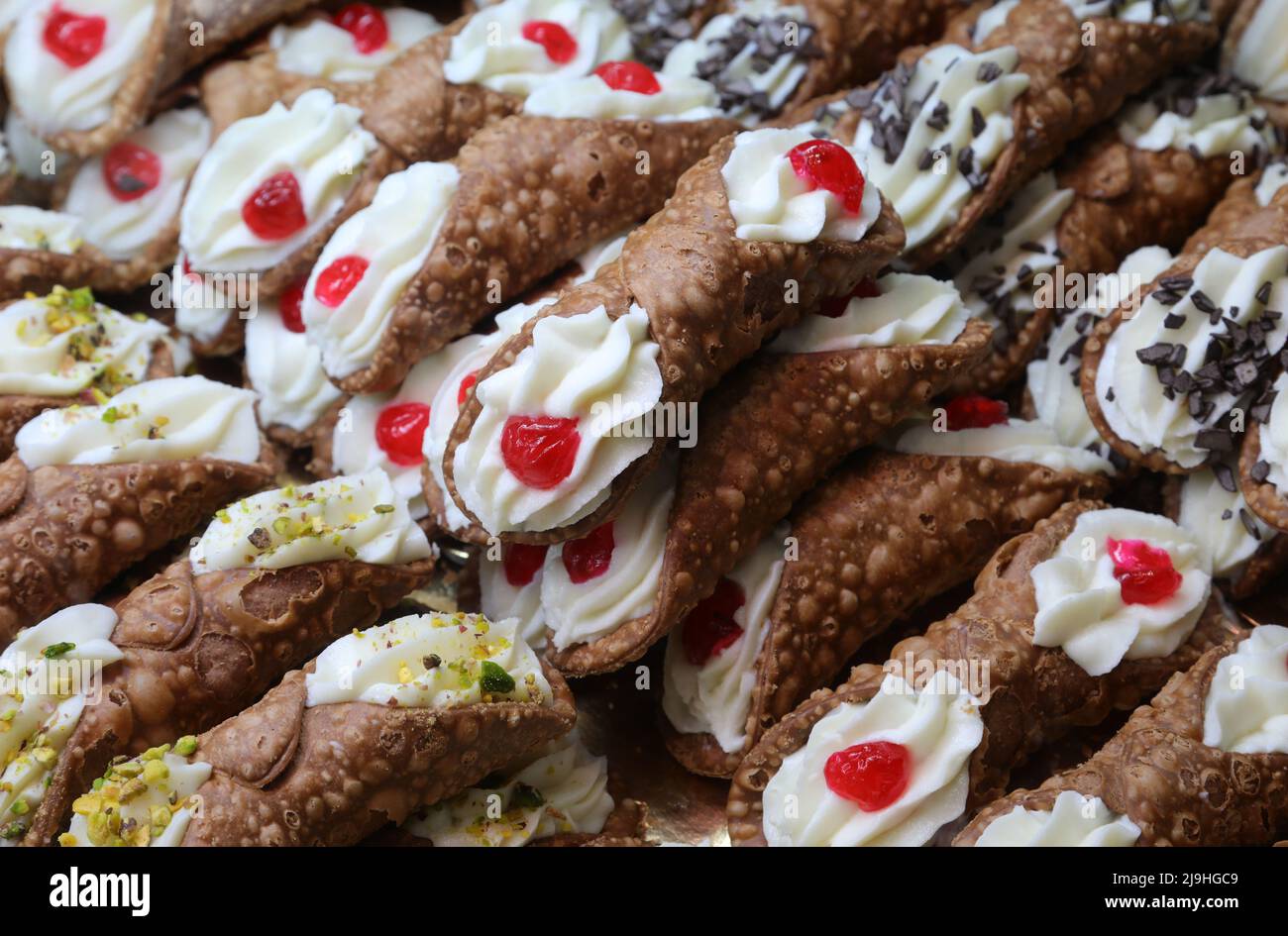 pastries with red cherry called SICILIAN CANNOLI which are the typical dessert of the island of SICILY in the Mediterranean Sea in Italy in Europe Stock Photo