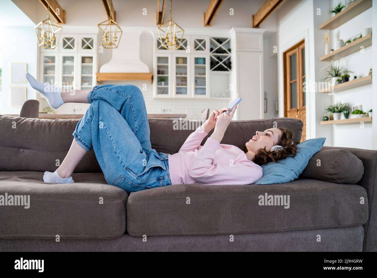 Woman using smart phone lying on sofa Stock Photo