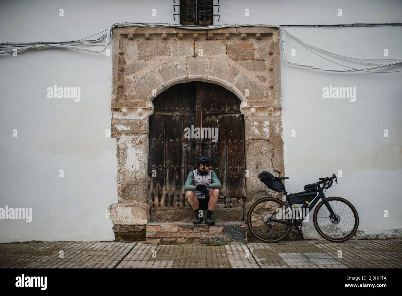 Cyclist with bicycle sitting in front of old door Stock Photo