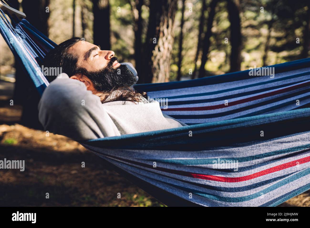 Bearded man with eyes closed resting in hammock Stock Photo