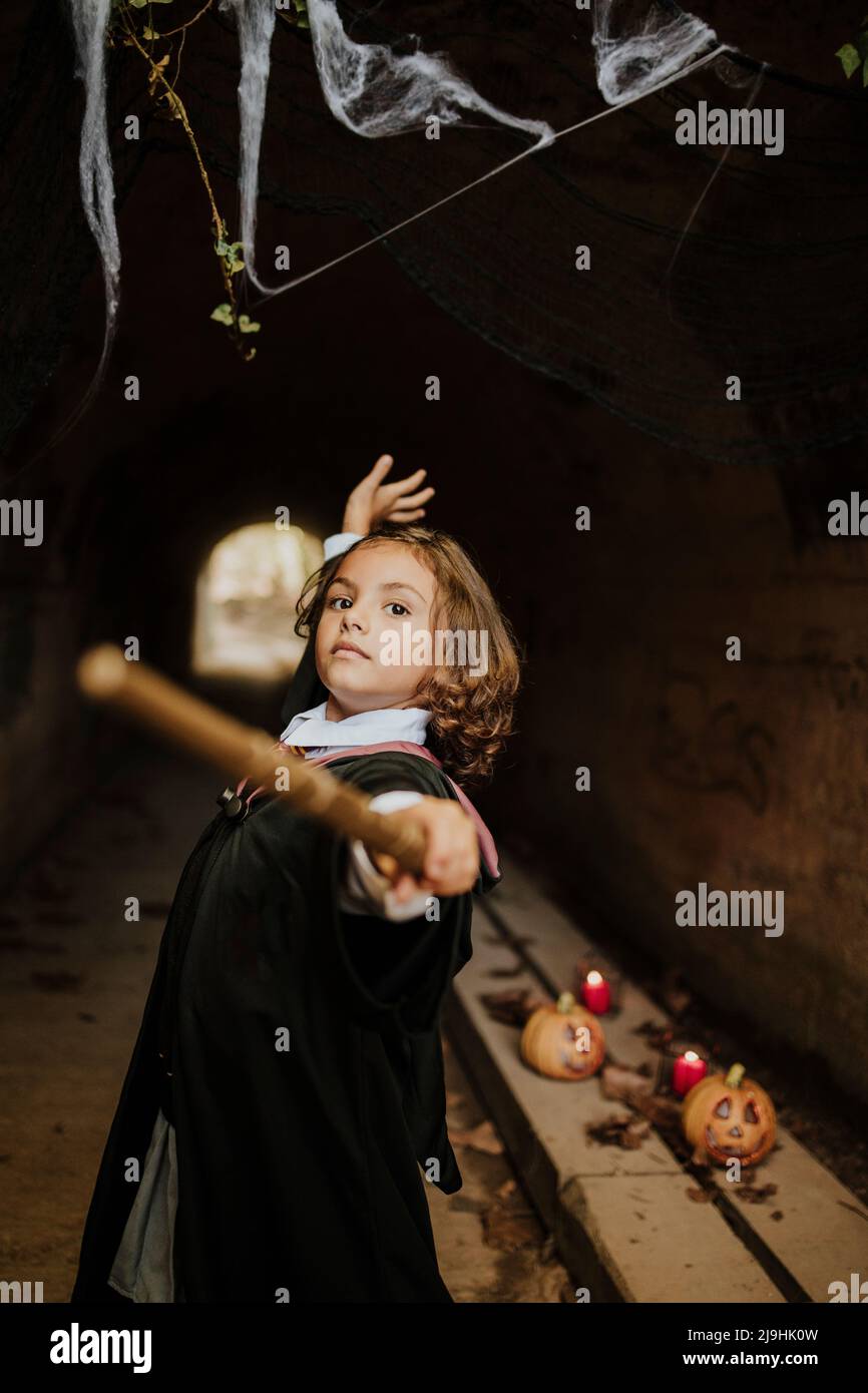 Girl wearing witch costume having fun in spooky tunnel at Halloween Stock Photo