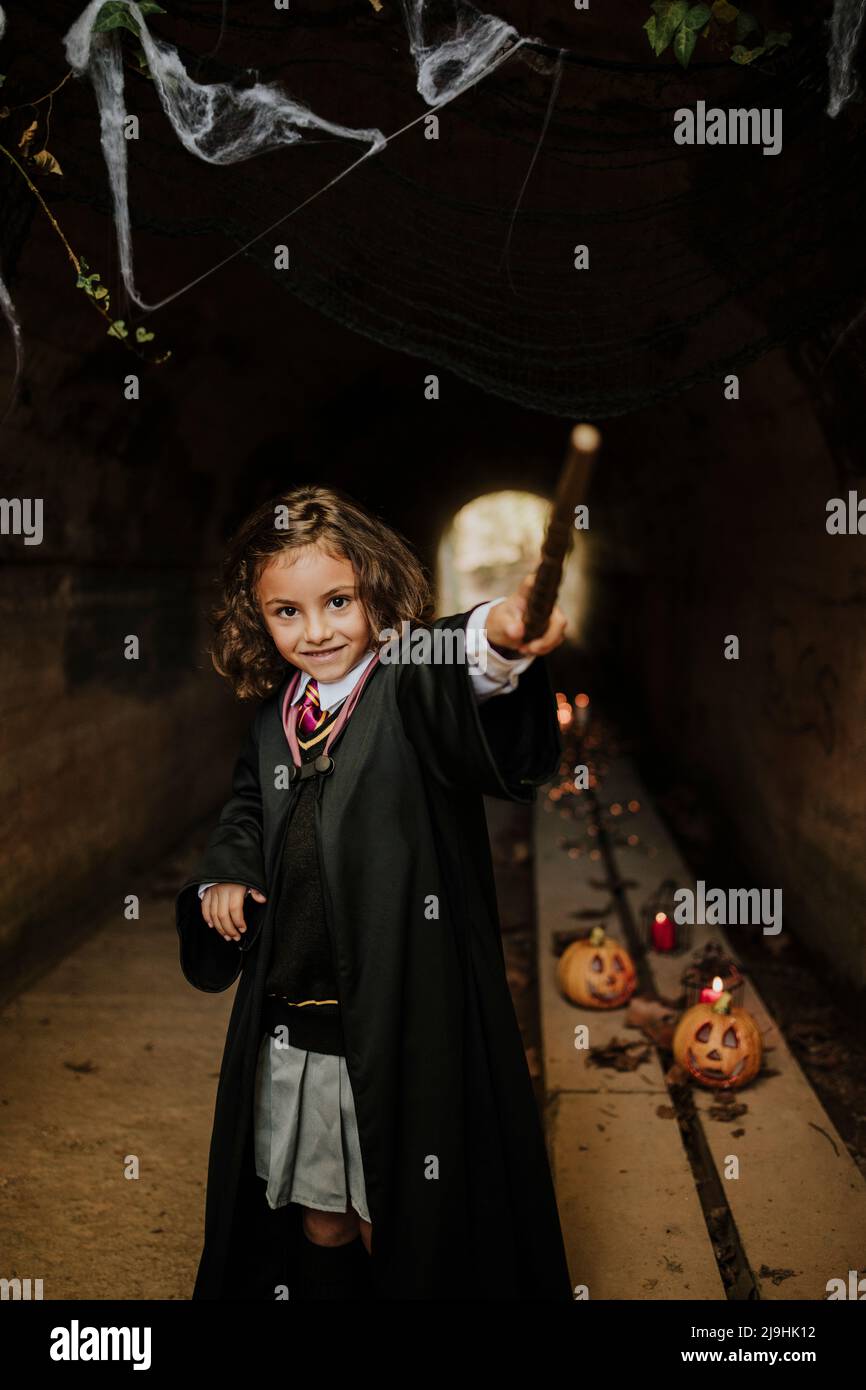 Smiling girl wearing witch costume having fun in tunnel at Halloween Stock Photo
