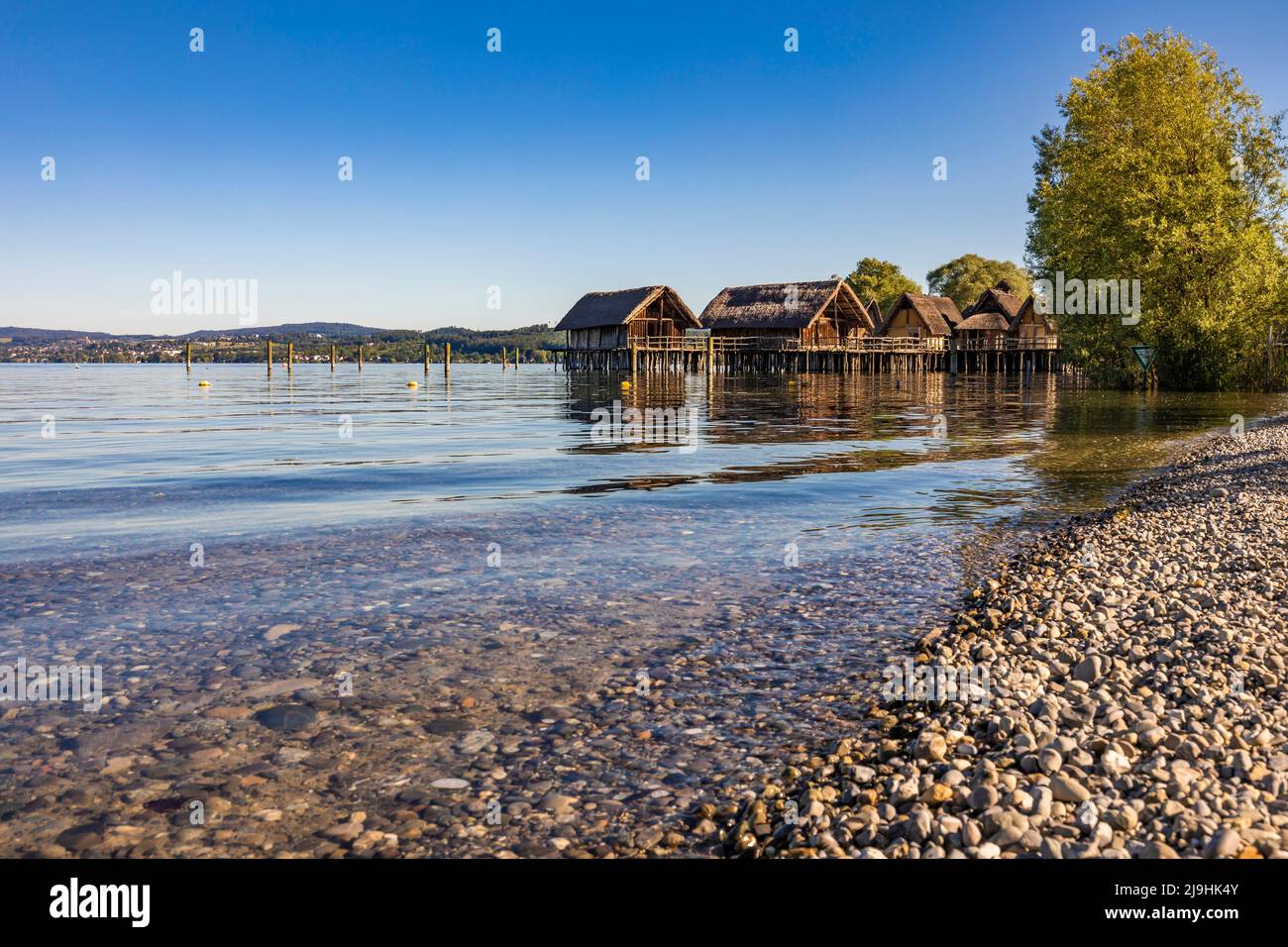 Germany, Baden-Wurttemberg, Unteruhldingen, Rocky shore of Lake Constance with Pile Dwelling Museum in background Stock Photo