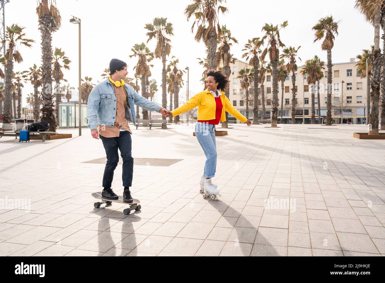 Happy couple holding hands skating together on footpath Stock Photo - Alamy