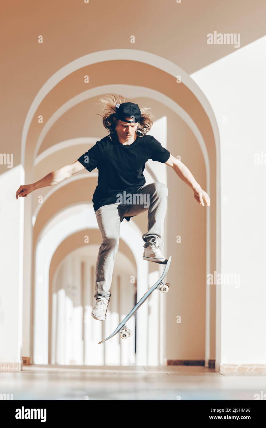 Man with skateboard jumping in arcade Stock Photo - Alamy