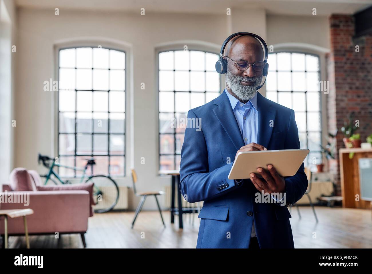 Smiling businessman with headset using tablet computer at home Stock Photo