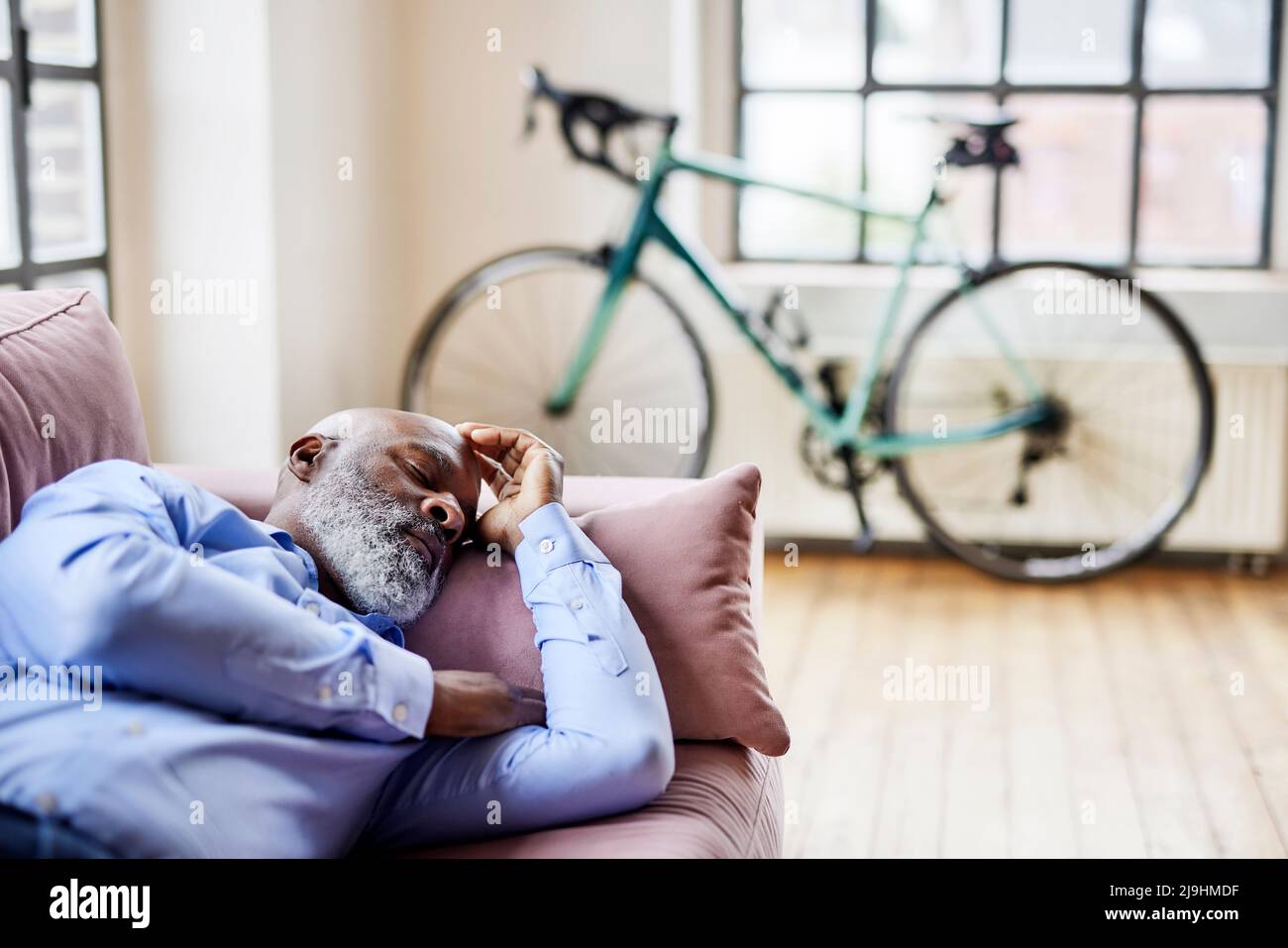 Mature businessman sleeping on sofa in living room at home Stock Photo ...