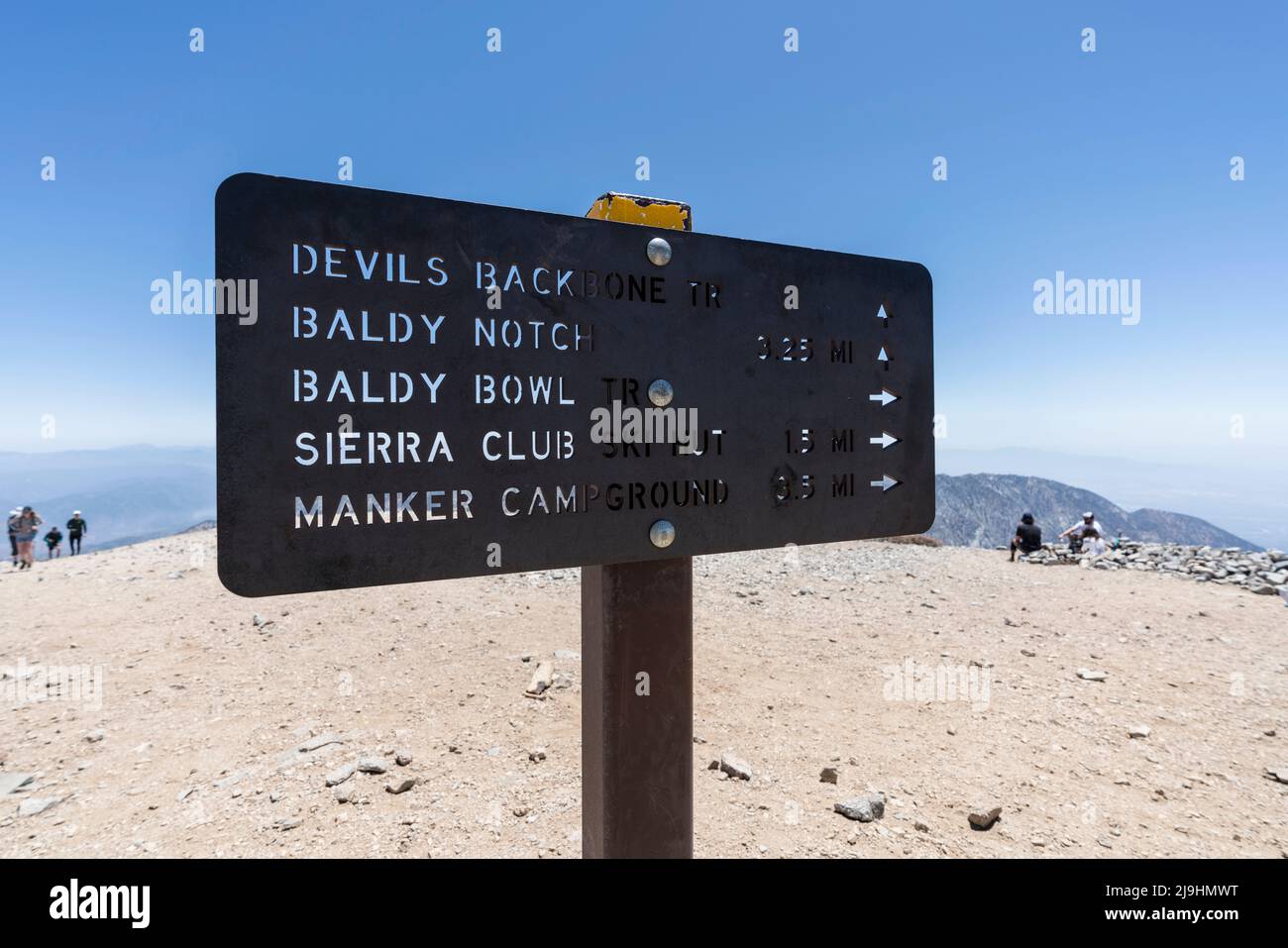 Mt Baldy, California, USA - May 22, 2022:  View of Devils Backbone trail sign and hikers on the summit of Mt Baldy in the San Gabriel Mountains. Stock Photo