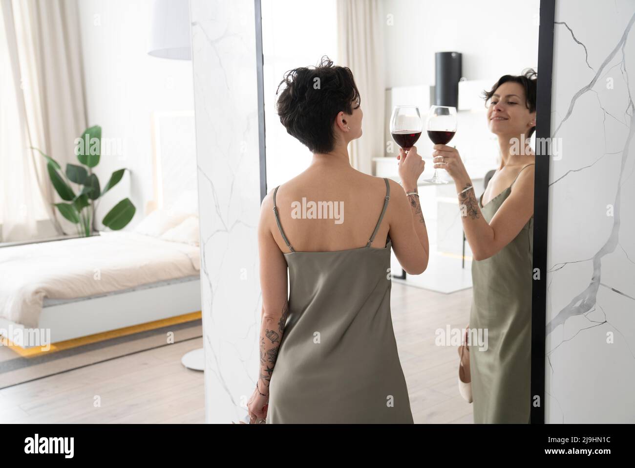 Smiling woman toasting wineglass at reflection on mirror at home Stock Photo