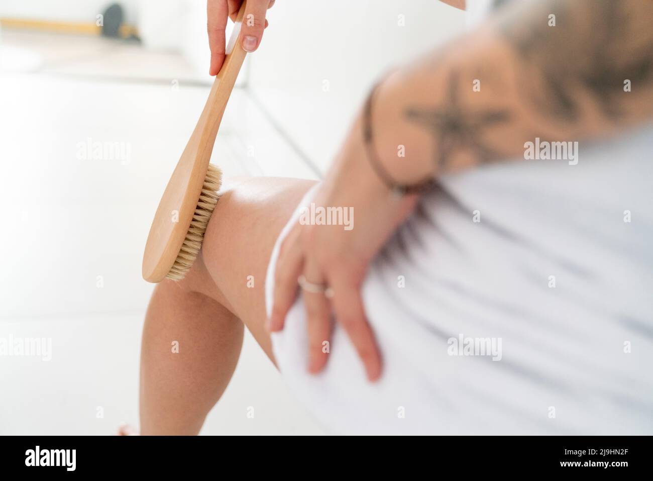 Woman exfoliating her legs with brush at home Stock Photo