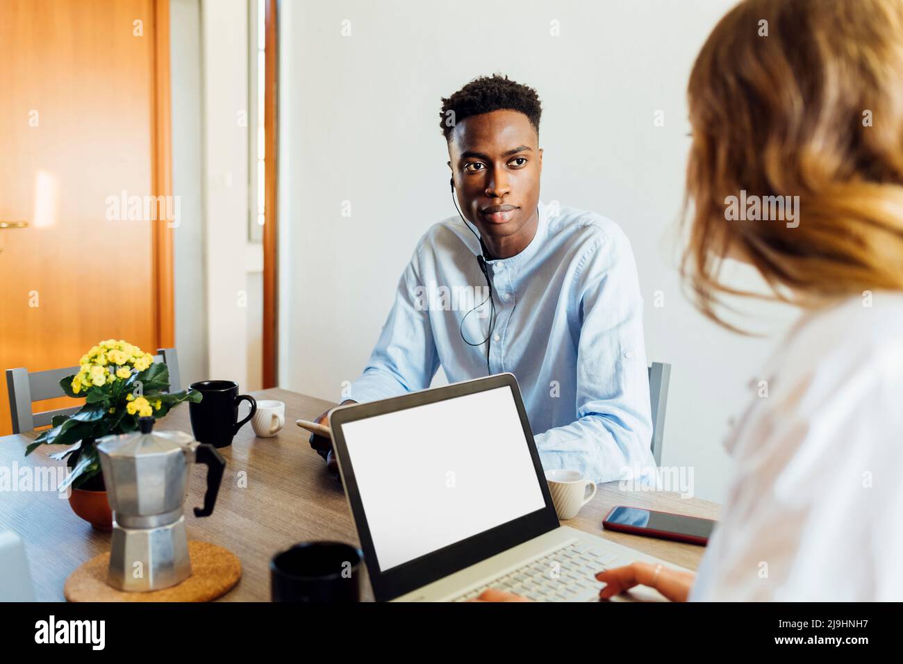 Young woman with laptop sitting by boyfriend at dining table Stock Photo