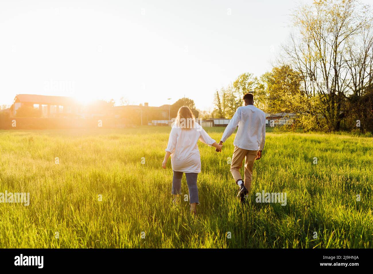 Couple holding hands walking on grass Stock Photo - Alamy