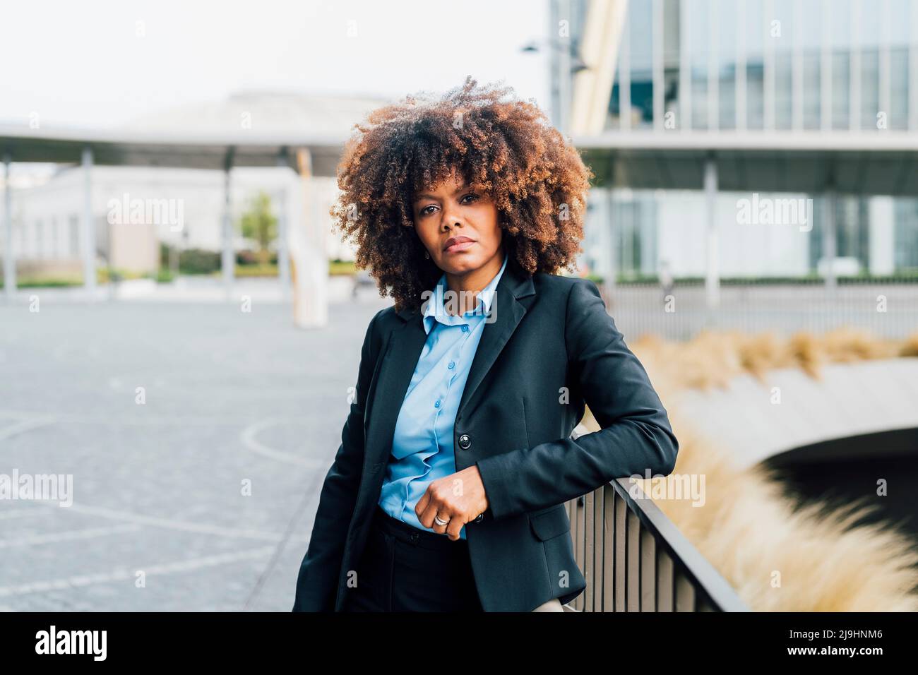 Confident Afro businesswoman standing by railing Stock Photo