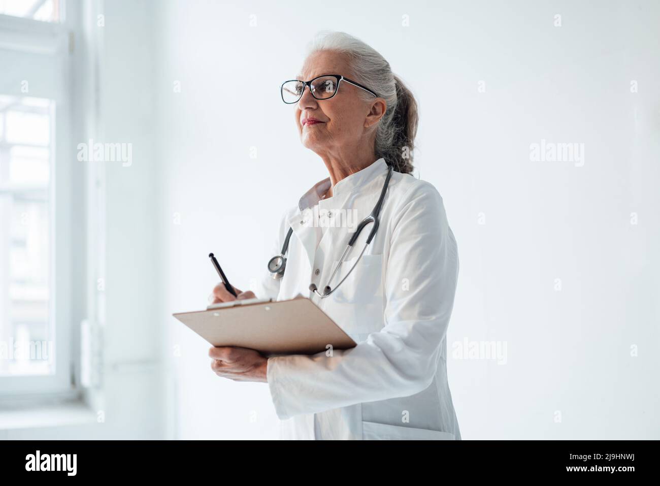 Doctor wearing eyeglasses standing with clipboard Stock Photo Alamy