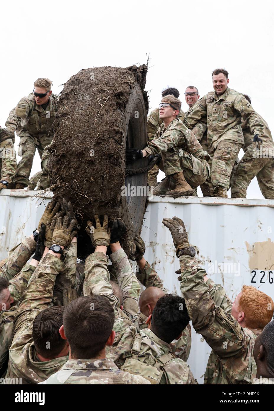 Fort Carson, United States. 23rd May, 2022. U.S. Army soldiers assigned to the 4th Infantry Division, help thrust a giant tire over a muddy container wall during the Utah Beach challenge event at Fort Carson, May 23, 2022 in Fort Carson, Colorado. The event held during Ivy Week requires teams of soldiers to carry a 300-pound tire over a muddy obstacle course. Credit: SSgt. Matthew Lumagui/U.S. Army/Alamy Live News Stock Photo