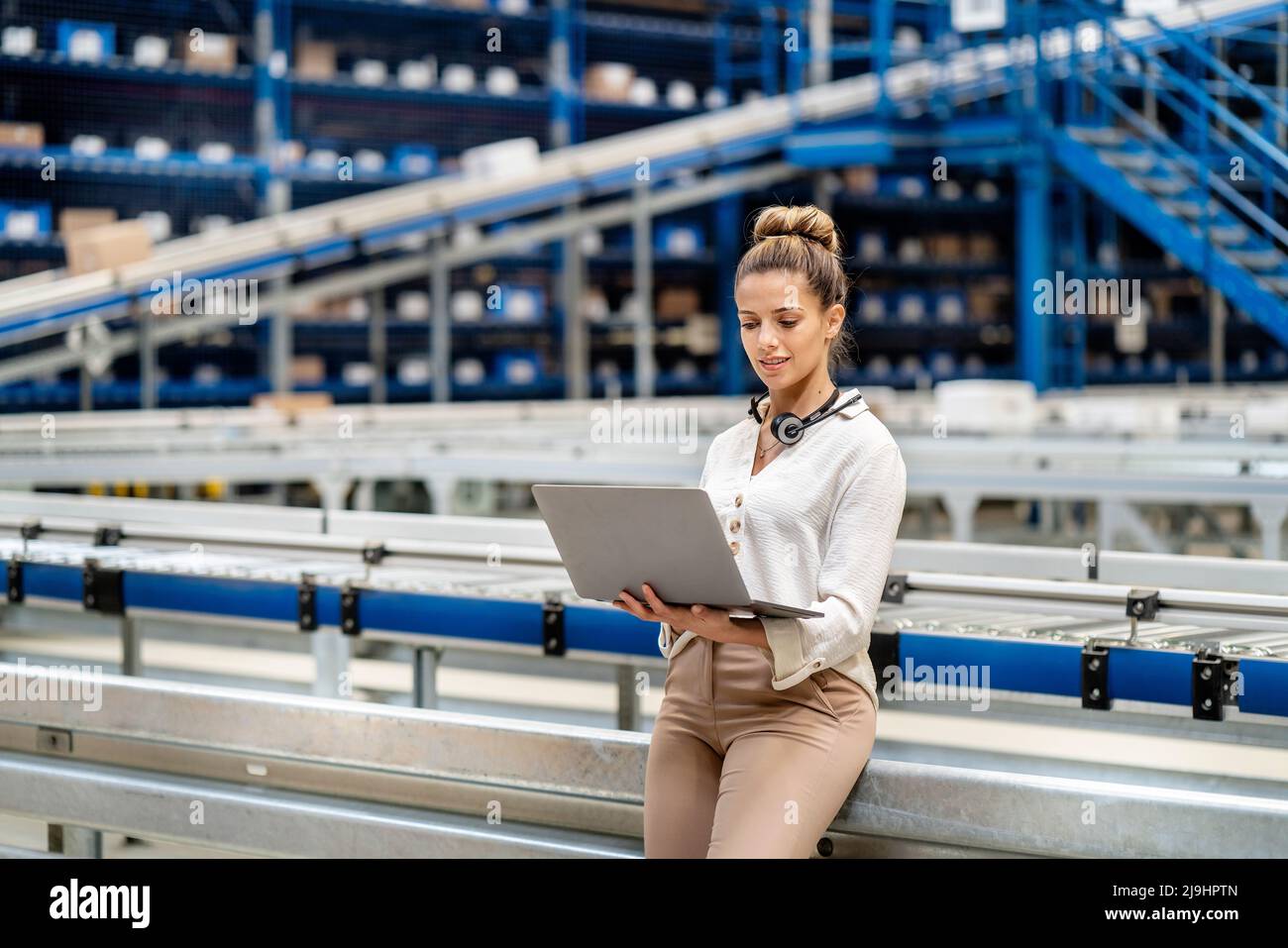 Woman using laptop in warehouse Stock Photo