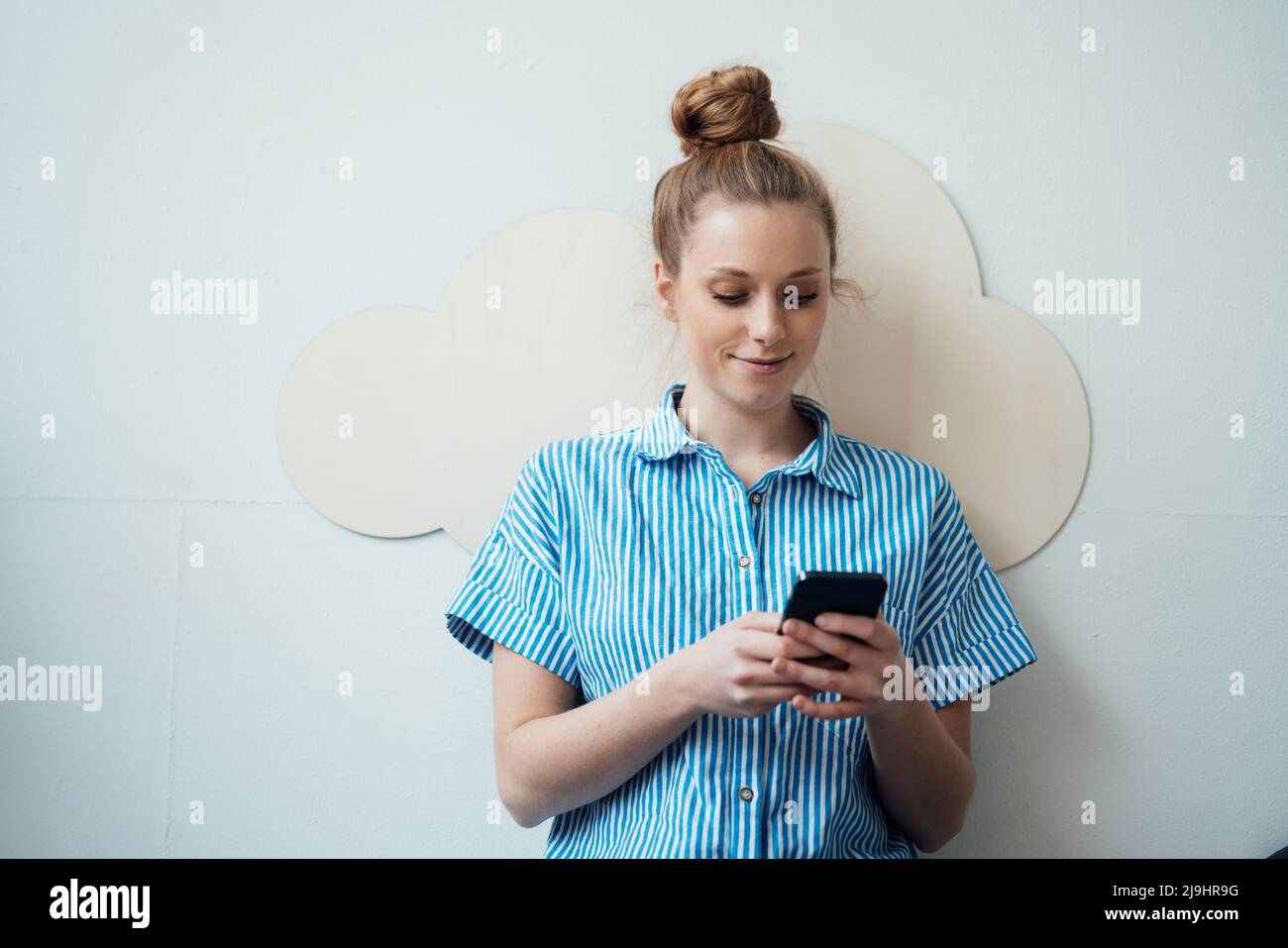 Freelancer using smart phone in front of wall Stock Photo