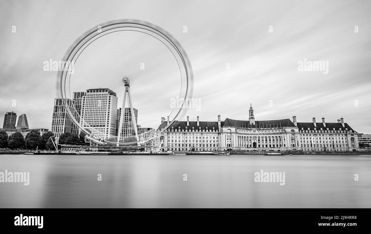 A black and white long exposure of the London Eye ferris wheel rotating on the Southbank on the edge of the River Thames in London pictured in May 202 Stock Photo