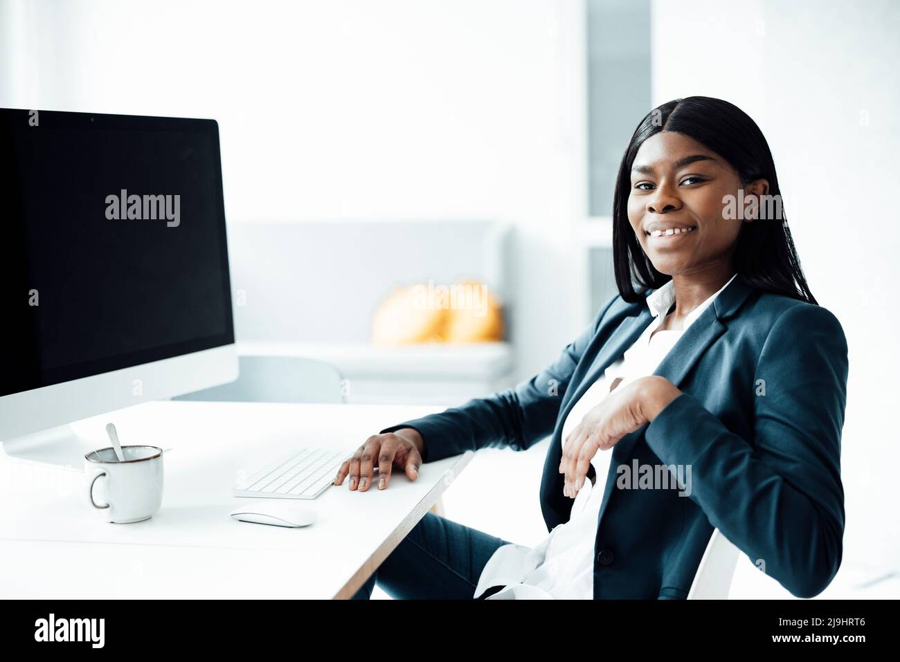 Smiling businesswoman with desktop PC at desk in office Stock Photo