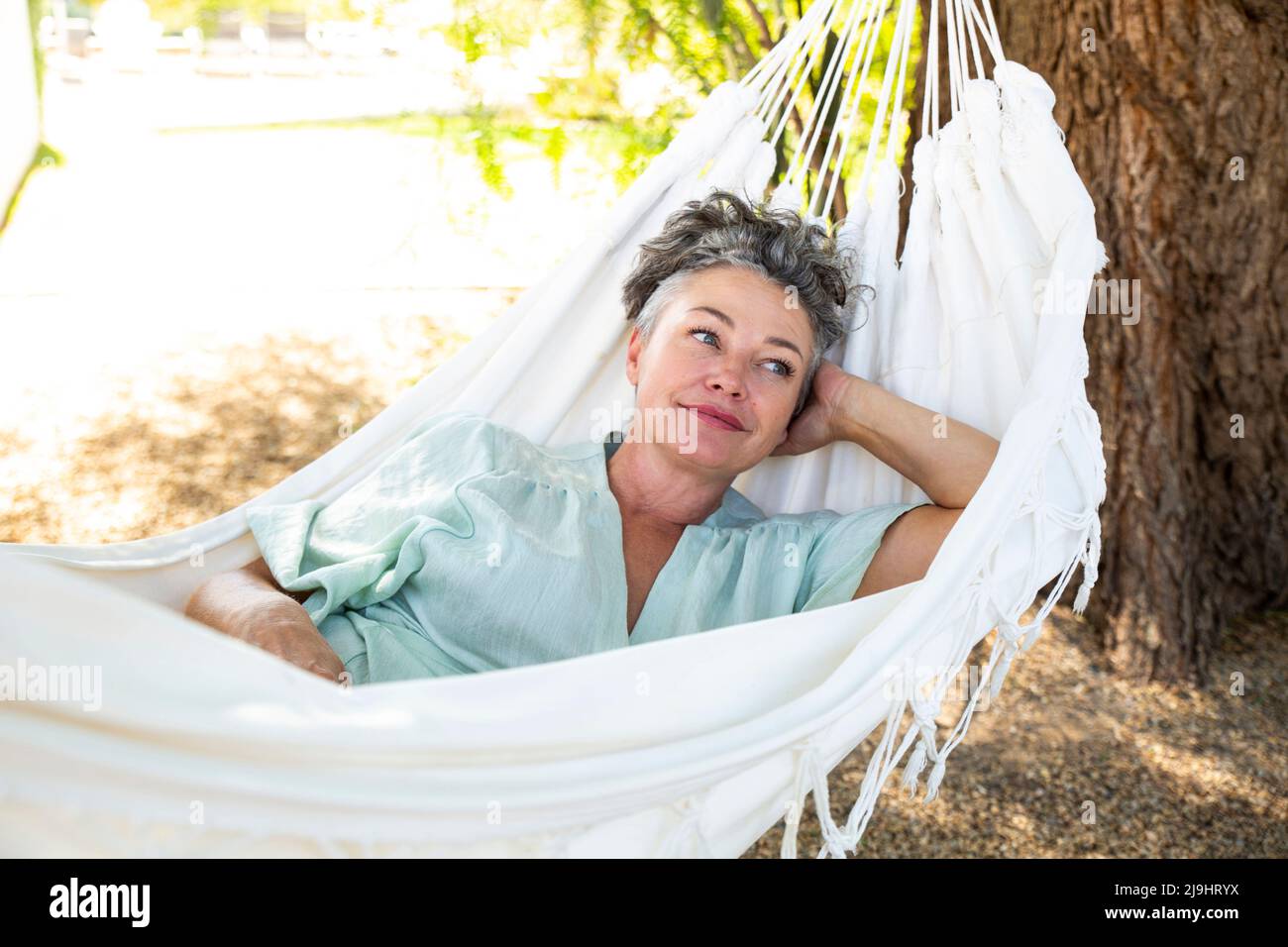 Woman with hand behind head lying in hammock Stock Photo