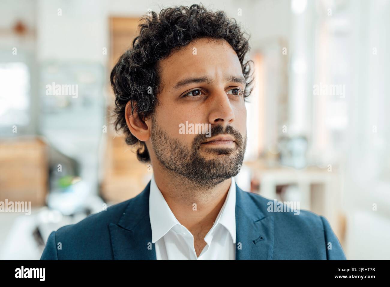 Thoughtful businessman standing in office Stock Photo